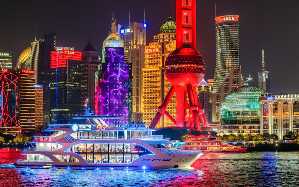 Cruise ship sailing past the illuminated Oriental Pearl Tower in Shanghai.