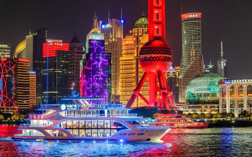 Cruise ship sailing past the illuminated Oriental Pearl Tower in Shanghai.