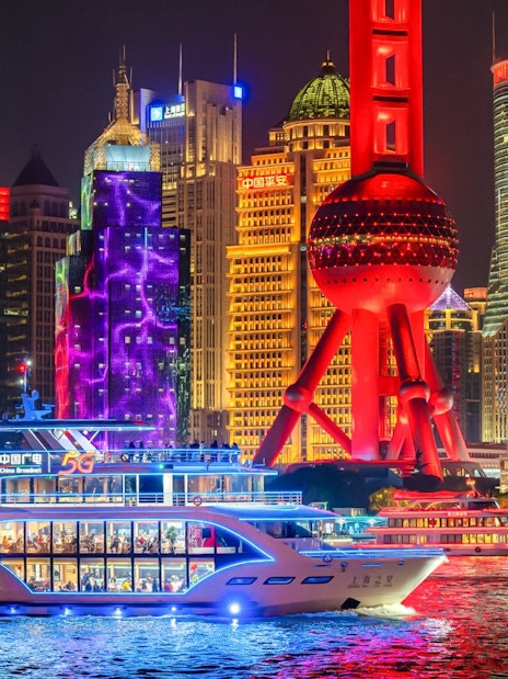 Cruise ship sailing past the illuminated Oriental Pearl Tower in Shanghai.
