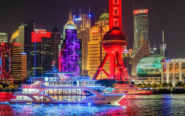 Cruise ship sailing past the illuminated Oriental Pearl Tower in Shanghai.