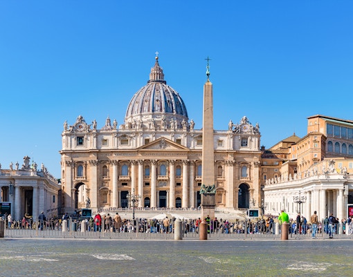 Vatican City St Peter's Basilica exterior with tourists in foreground.