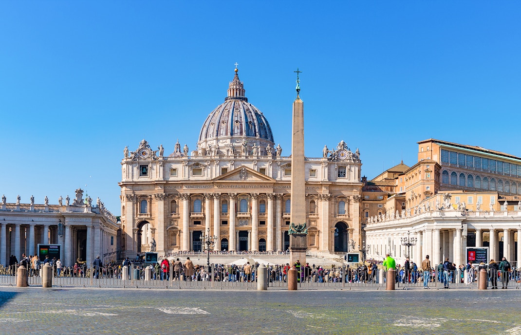 Vatican City St Peter's Basilica exterior with tourists in foreground.