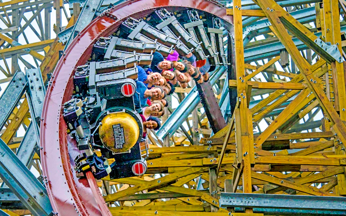 Riders on Steel Vengeance roller coaster at Cedar Point in a wooden structure loop.
