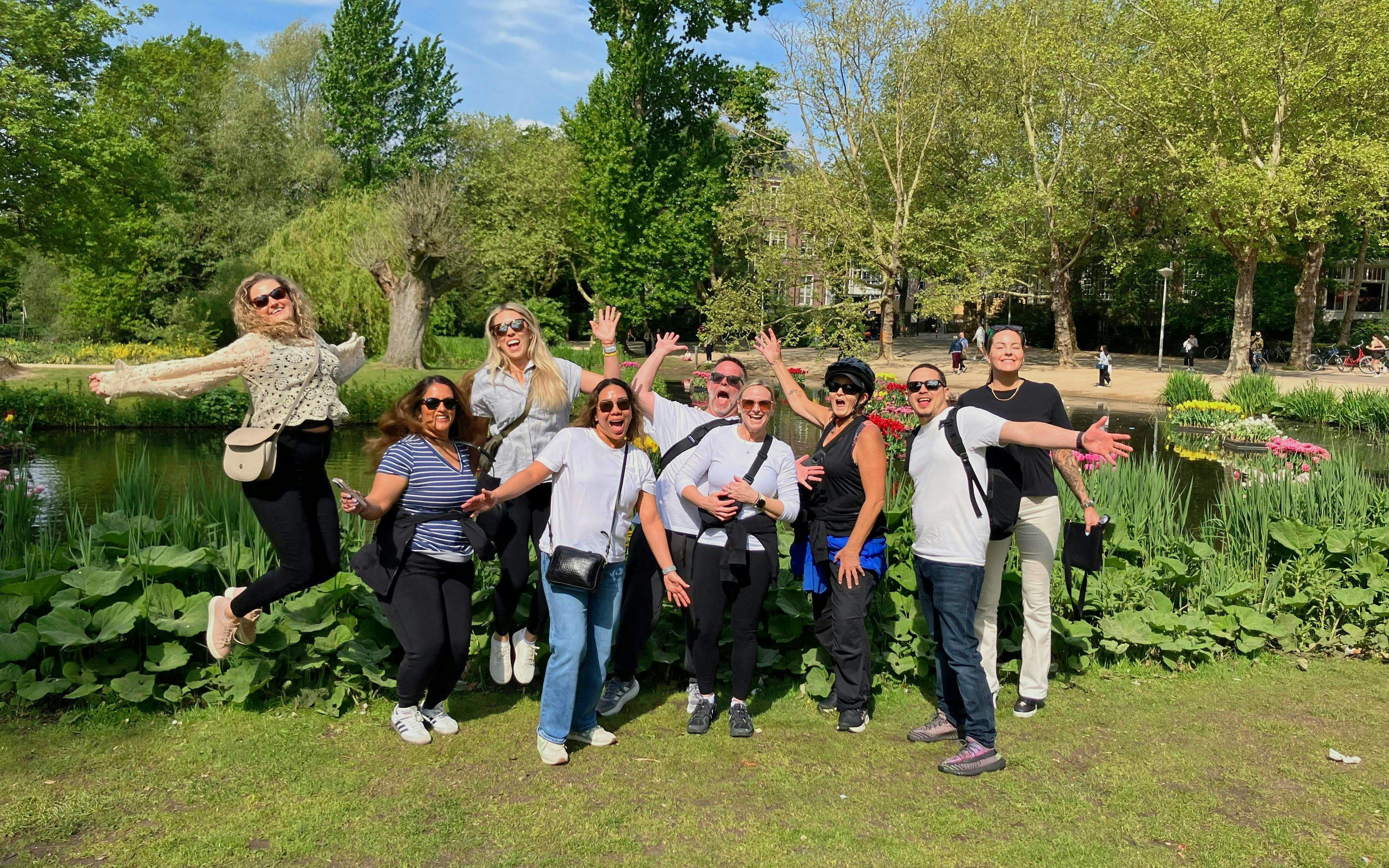 Group enjoying a bike tour in a city park with lush greenery and a pond.