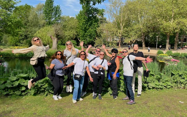 Group enjoying a bike tour in a city park with lush greenery and a pond.