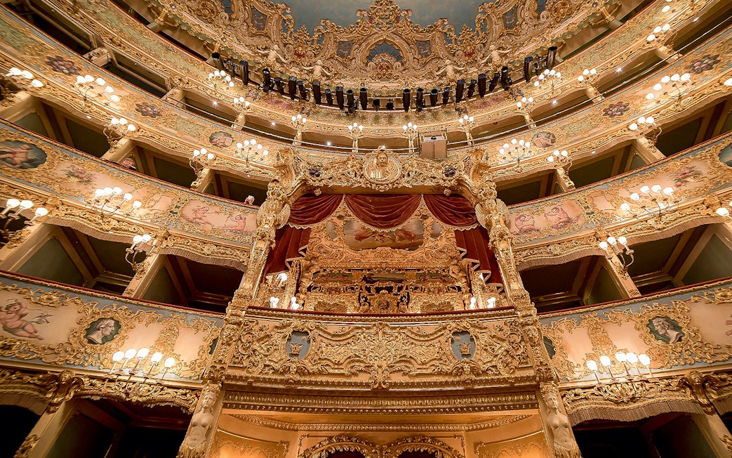 Ornate interior of Fenice Theater with gilded balconies and chandeliers.