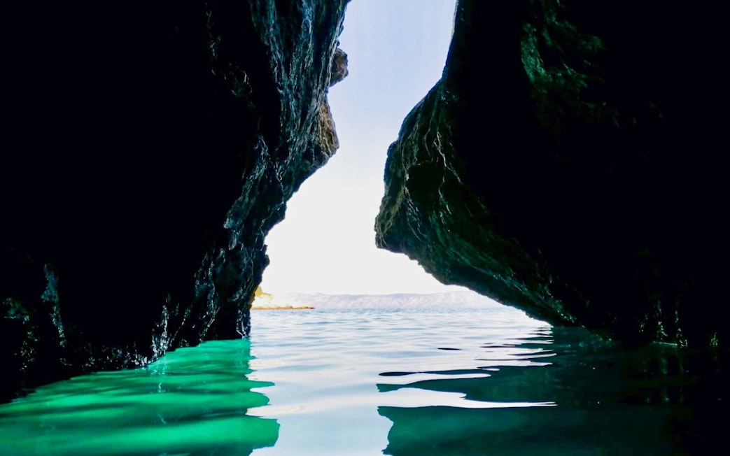 Hidden cave entrance with turquoise water on Hvar Island, Croatia.