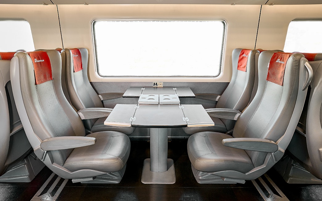 Trenitalia standard class seats with table in train interior.