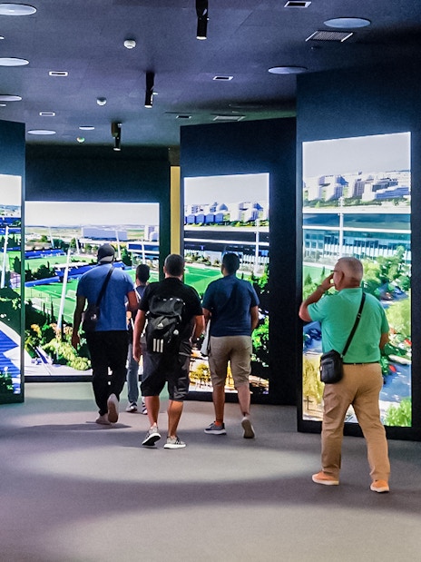 Tourists viewing digital displays at Santiago Bernabeu stadium exhibit.