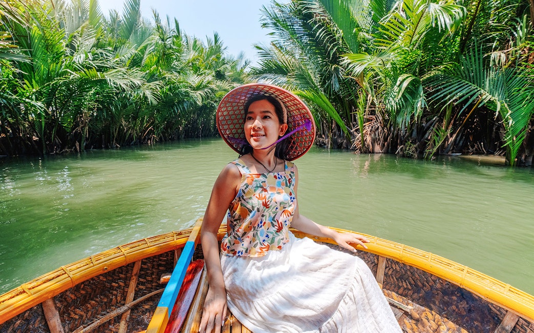 Woman enjoying basket boat tour on a lush green lagoon in Hoi An.