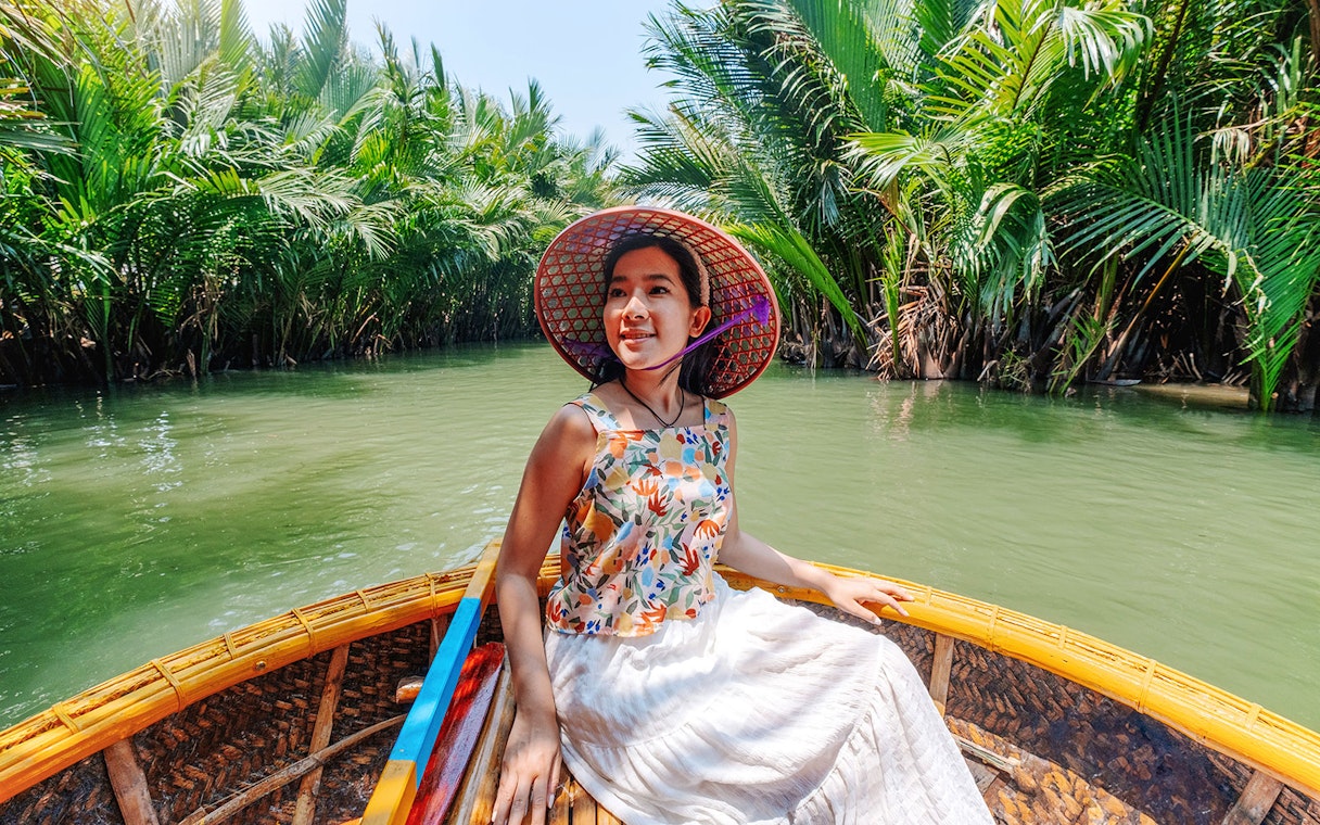 Woman enjoying basket boat tour on a lush green lagoon in Hoi An.