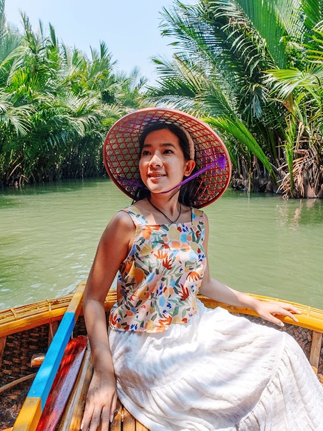 Woman enjoying basket boat tour on a lush green lagoon in Hoi An.