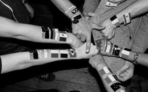 Arms with international flag wristbands at Barcelona Language Exchange Night.