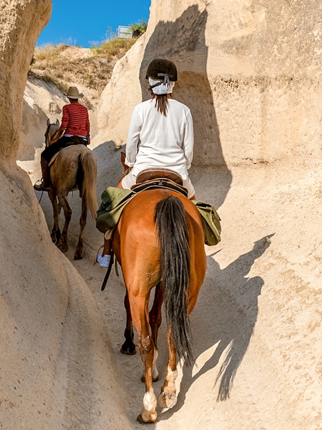 Horseback riders navigating narrow valley in Cappadocia, Turkey.