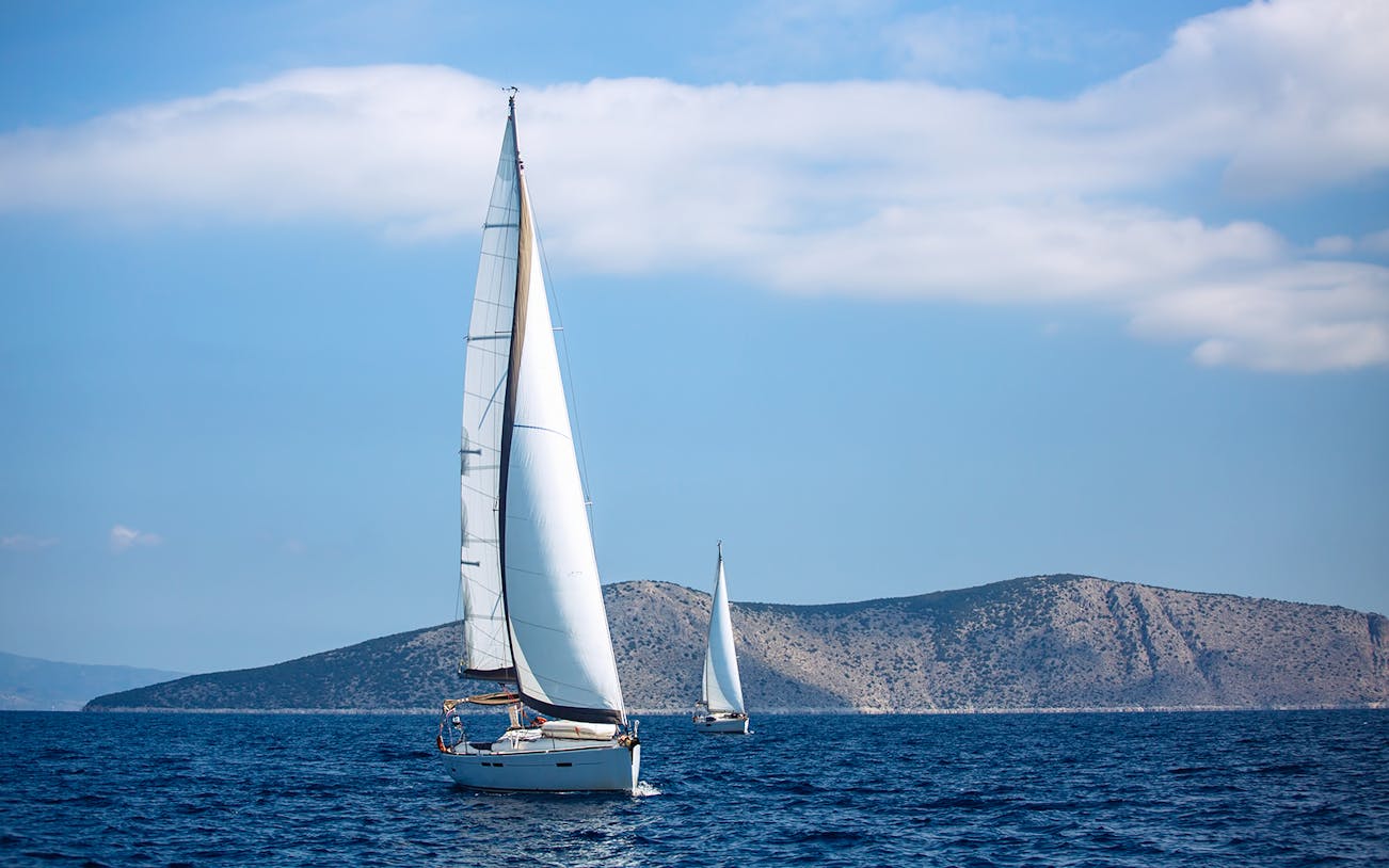Sailboats on the Aegean Sea near Santorini during sunset tour.