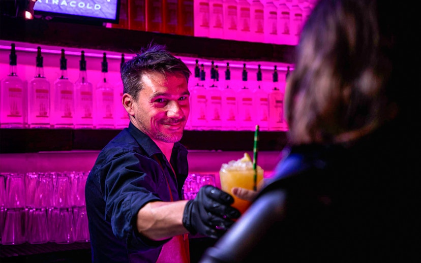 Bartender serving a cocktail at Icebar Amsterdam with vibrant lighting.