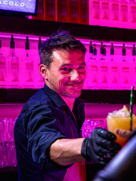 Bartender serving a cocktail at Icebar Amsterdam with vibrant lighting.