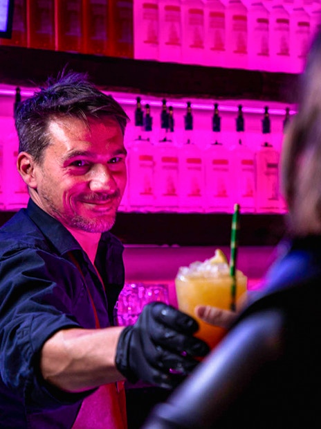 Bartender serving a cocktail at Icebar Amsterdam with vibrant lighting.