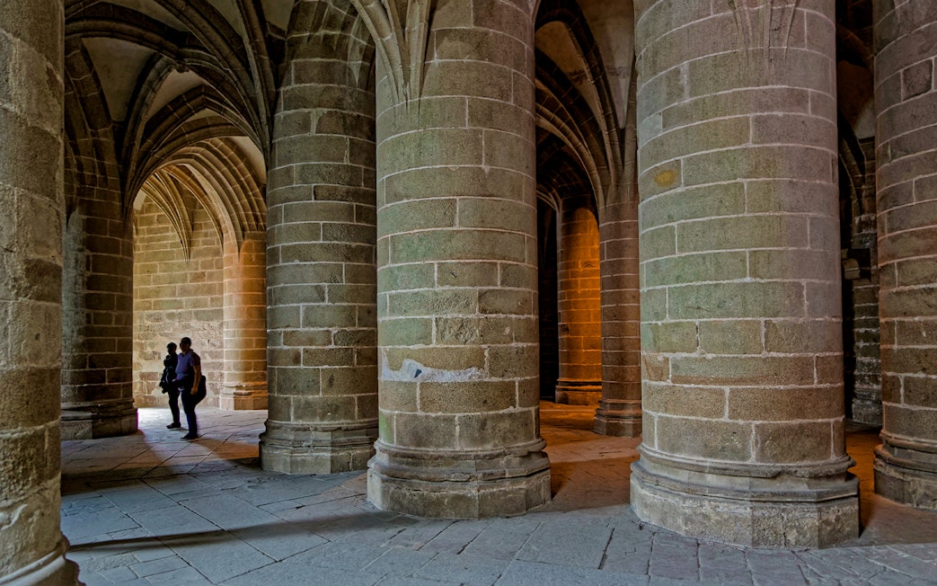 Great pillar hall in Mont Saint Michel with towering columns and arched ceilings.