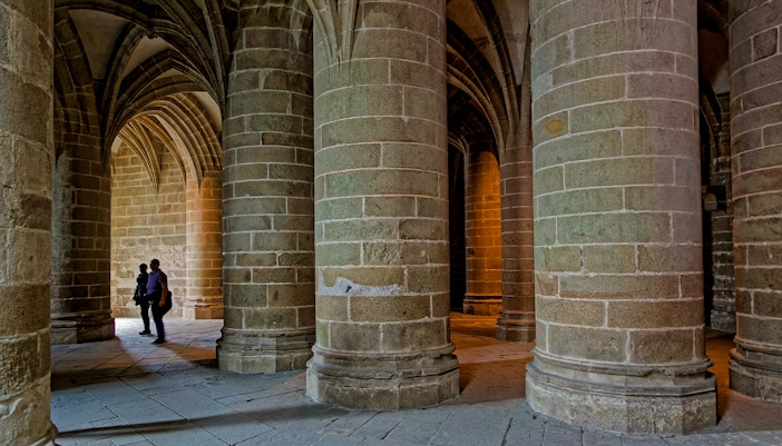 Great pillar hall in Mont Saint Michel with towering columns and arched ceilings.