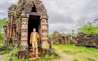 Tourist exploring ancient temple ruins at My Son Sanctuary, Vietnam.