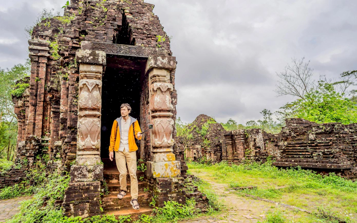 Tourist exploring ancient temple ruins at My Son Sanctuary, Vietnam.
