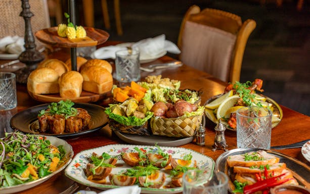 Te Pā Tū Maori feast with seasonal dishes and traditional bread on a wooden table.