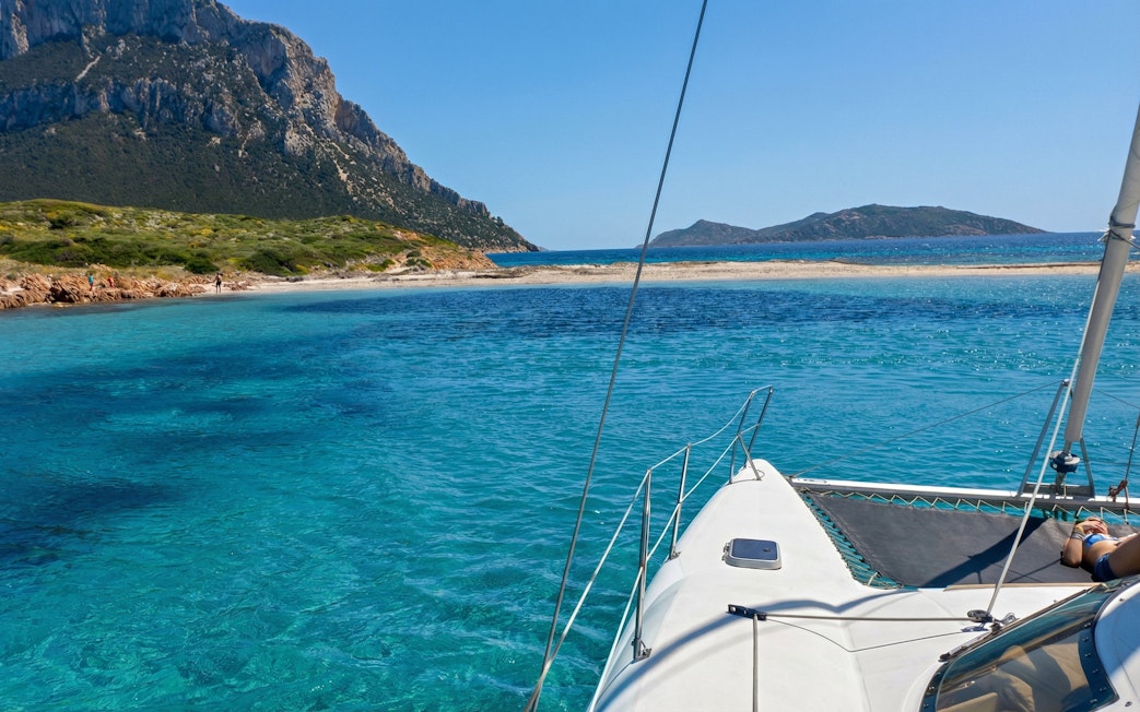 Catamaran sailing in clear waters of Area Marina Protetta Tavolara, Sardinia.