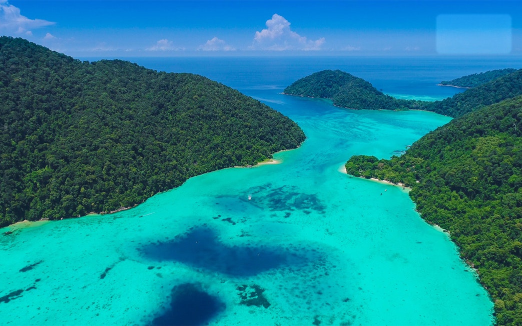 Aerial view of Surin Islands' lush green coastline and turquoise waters.