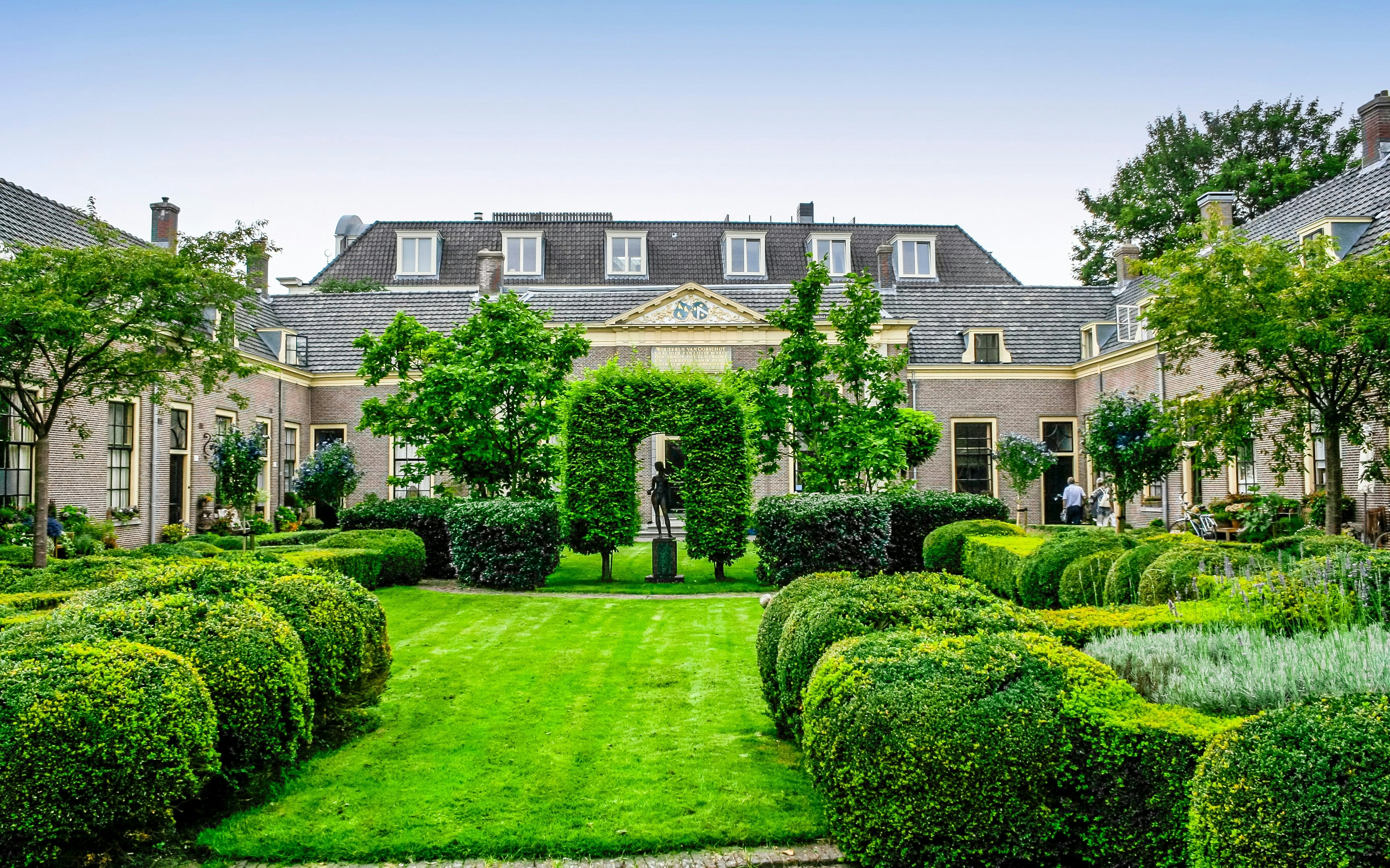 Hofje courtyard with manicured gardens and historic buildings in Haarlem.