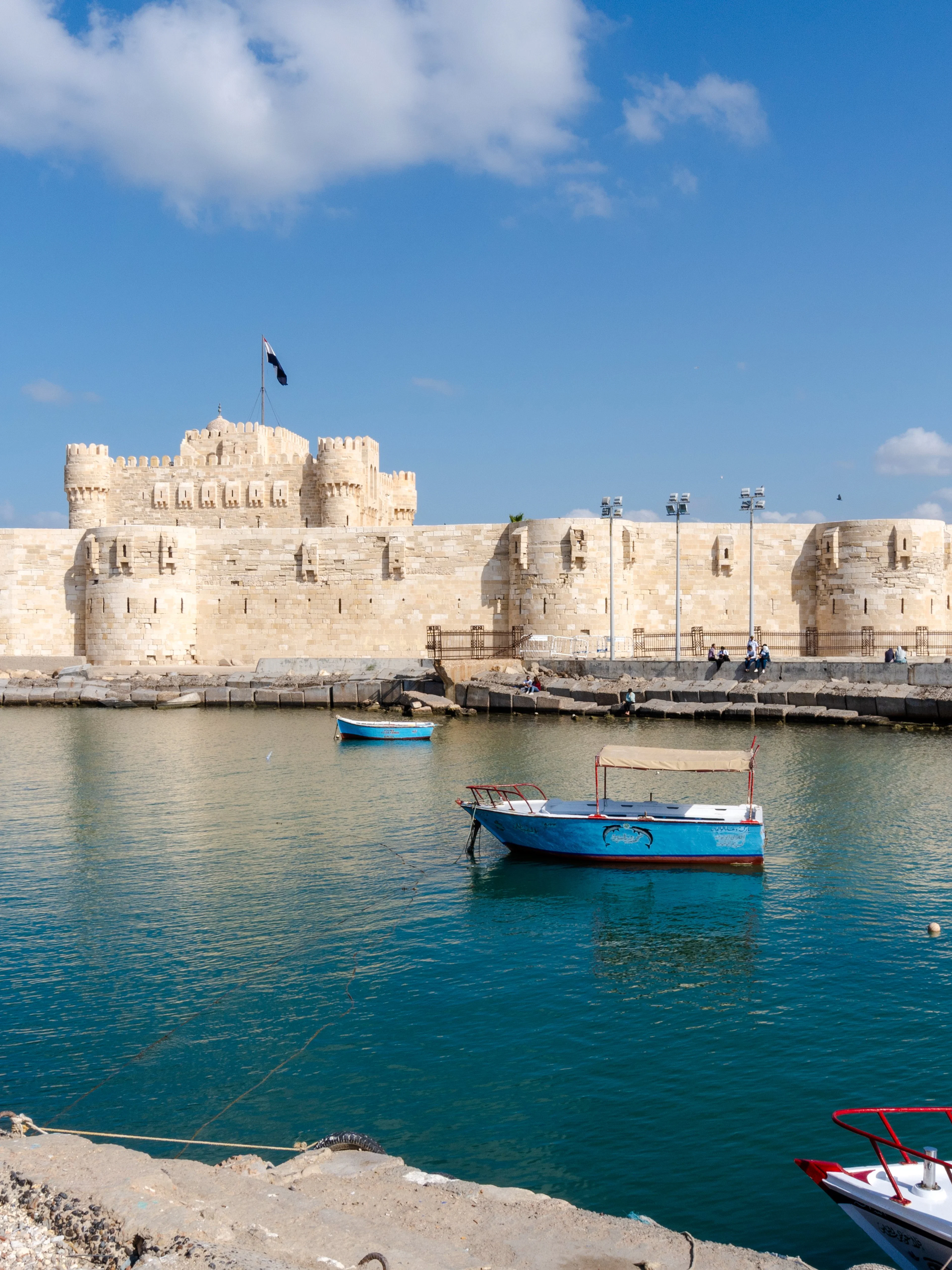 Citadel of Alexandria viewed from the sea with boats on a sunny day.