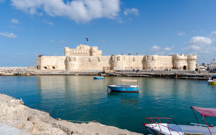 Citadel of Alexandria viewed from the sea with boats on a sunny day.