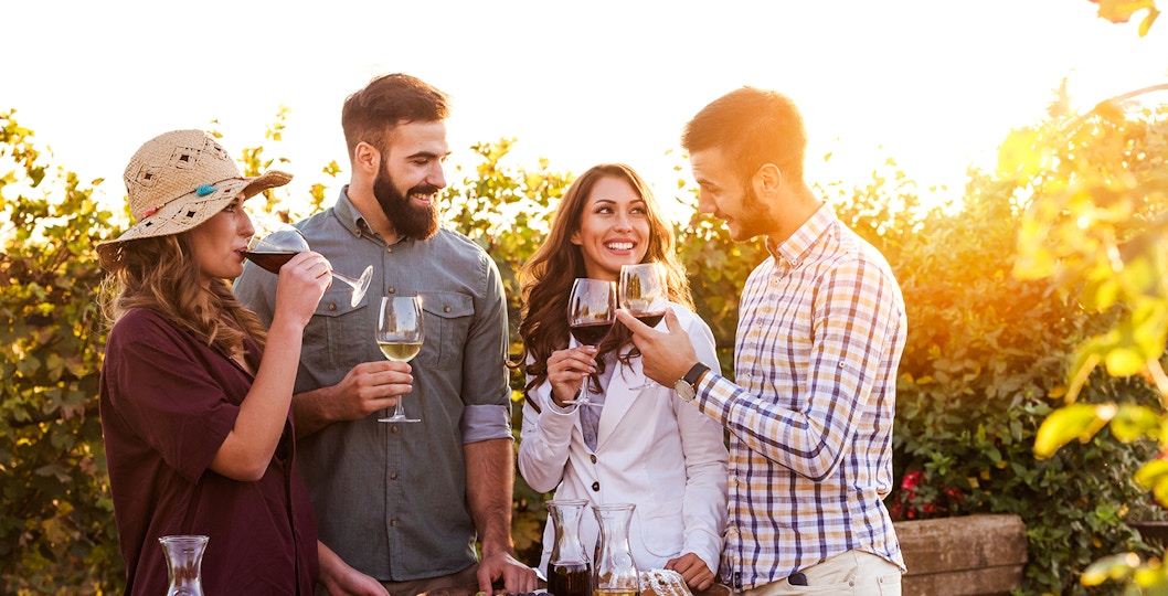 Group enjoying wine tasting in a Saint-Émilion vineyard at sunset.