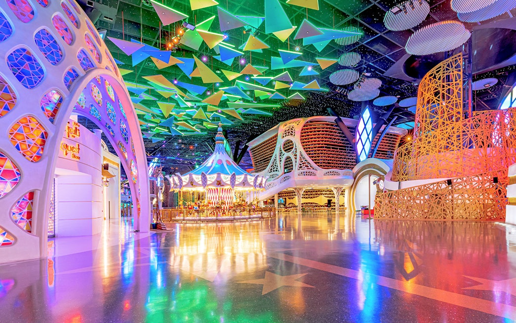 Doha Quest Theme Park interior with colorful carousel and geometric ceiling.