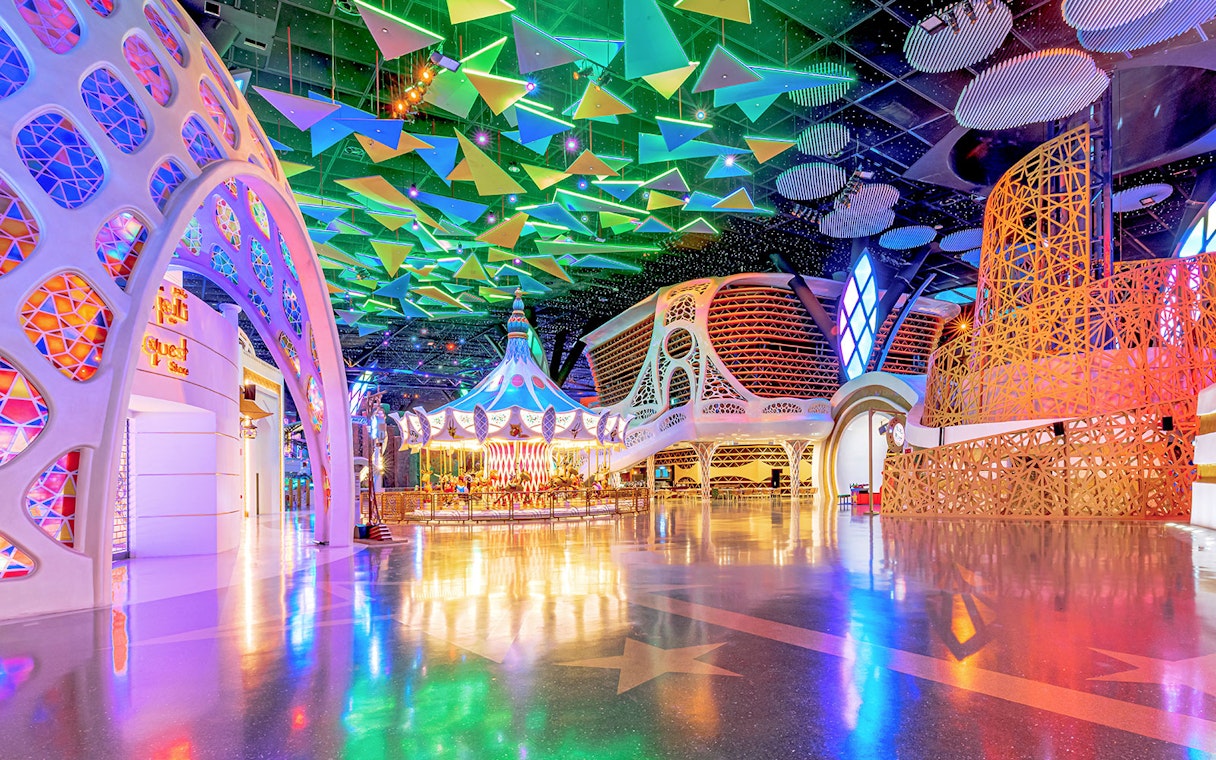 Doha Quest Theme Park interior with colorful carousel and geometric ceiling.