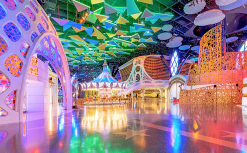 Doha Quest Theme Park interior with colorful carousel and geometric ceiling.
