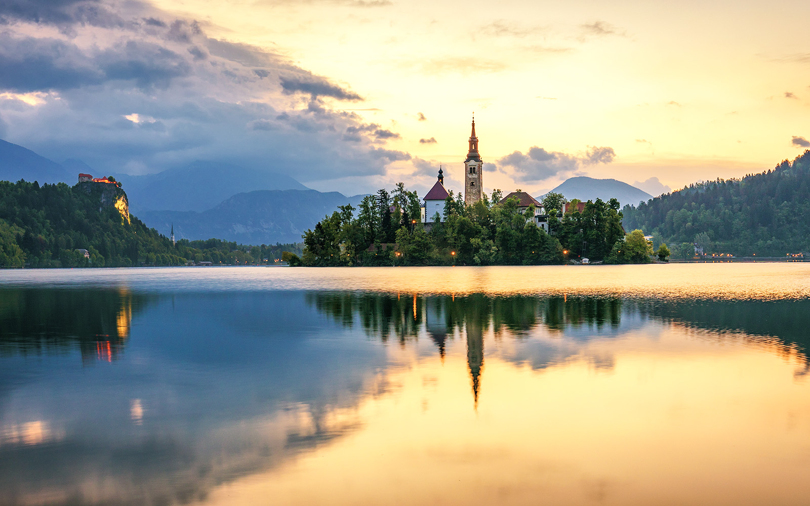 Church on Bled Island with castle and mountains at sunset, Lake Bled, Slovenia.
