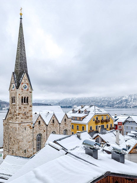 Hallstatt Church in winter, overlooking snowy rooftops and lake, Austria.