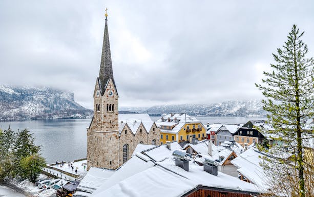 Hallstatt Church in winter, overlooking snowy rooftops and lake, Austria.