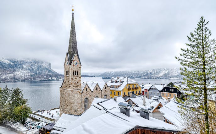 Hallstatt Church in winter, overlooking snowy rooftops and lake, Austria.