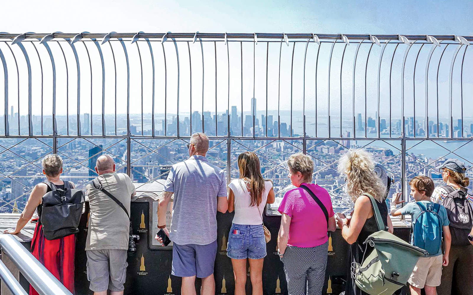 Visitors viewing New York City skyline from Empire State Building observatory.