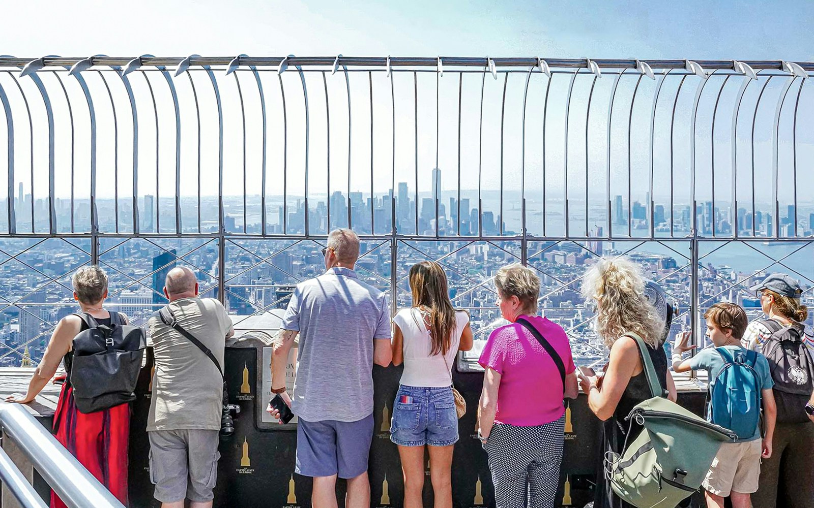 Visitors viewing New York City skyline from Empire State Building observatory.