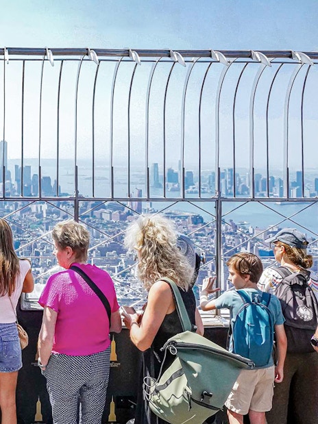 Visitors viewing New York City skyline from Empire State Building observatory.