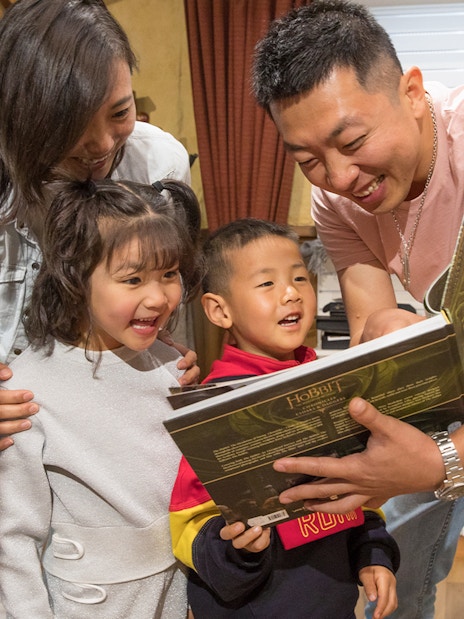 Family enjoying a book at Hobbiton Movie Set gift shop, New Zealand tour.