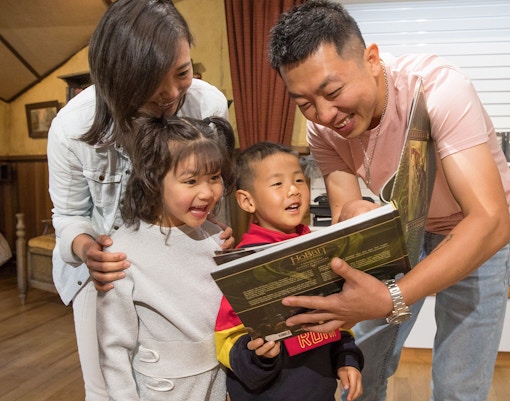 Family enjoying a book at Hobbiton Movie Set gift shop, New Zealand tour.