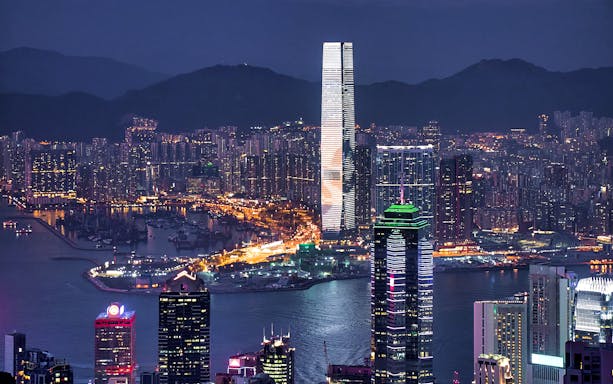 Hong Kong skyline at night with illuminated skyscrapers and harbor, view from ferry route to Macau.