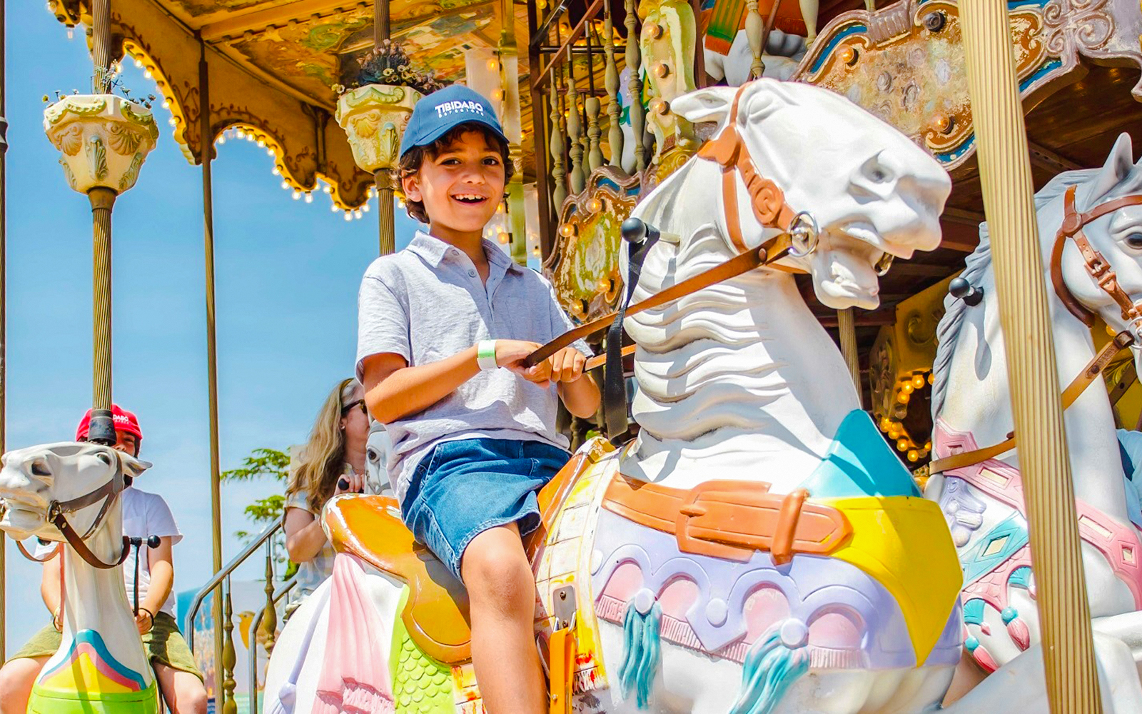 Child riding a colorful carousel horse at an amusement park.