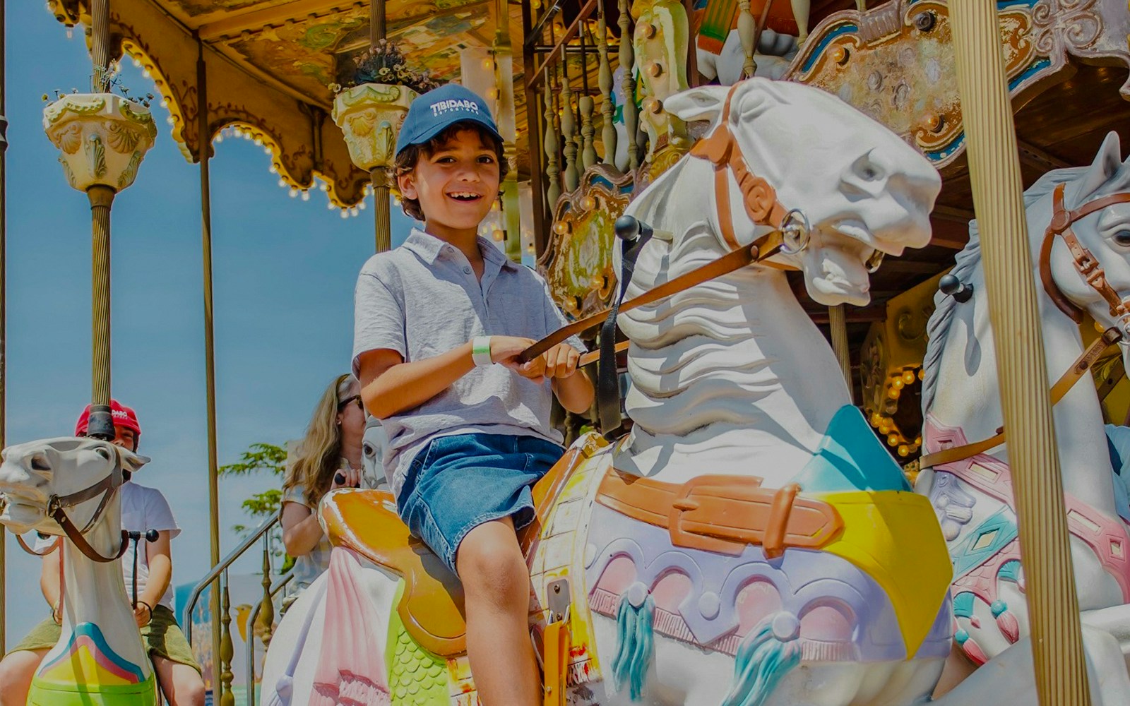 Child riding a colorful carousel horse at an amusement park.