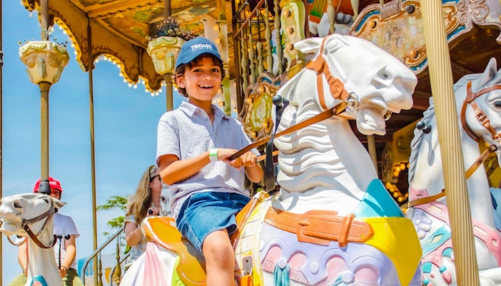 Child riding a colorful carousel horse at an amusement park.