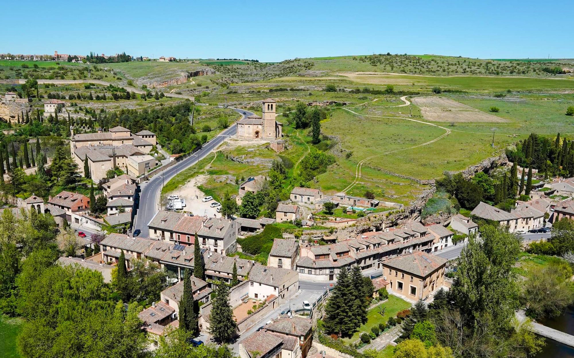 Aerial view of Segovia countryside with historic buildings and lush greenery.